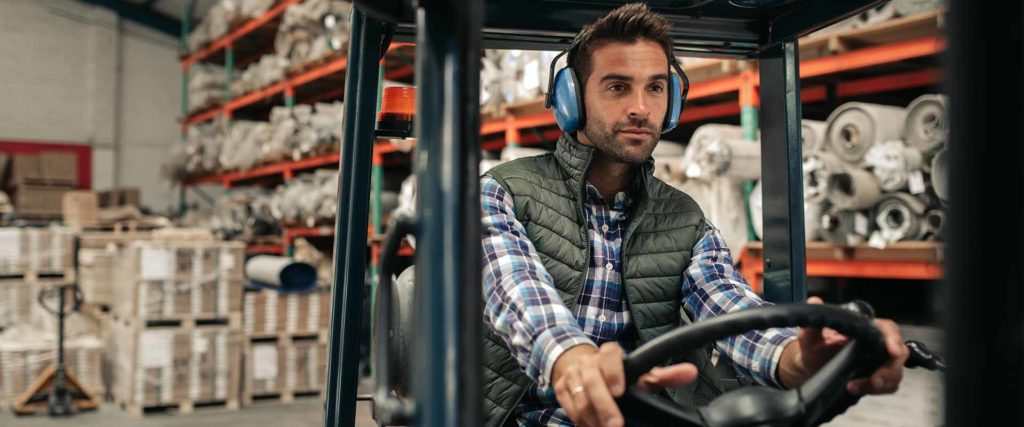 Worker driving a forklift while wearing ear protection