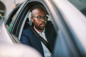 Black middle aged businessman driving a car to office