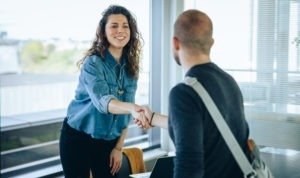 Businesswoman shaking hands with a job applicant. Female professional greets job candidate with a handshake in office boardroom.